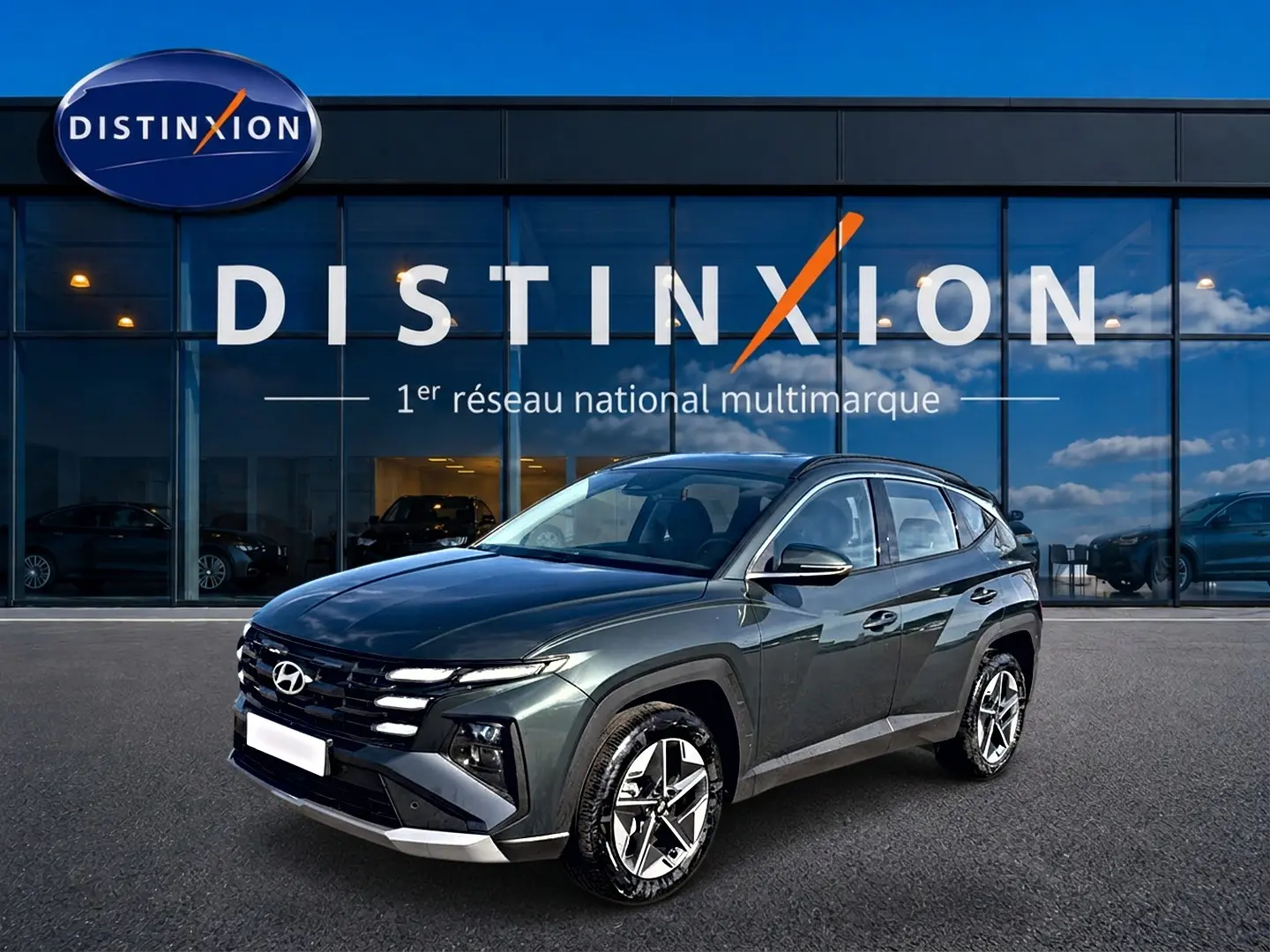 Hyundai Tucson 1.6 t-gdi 239 hybride vert en 3/4 avant droit devant un showroom Distinxion.