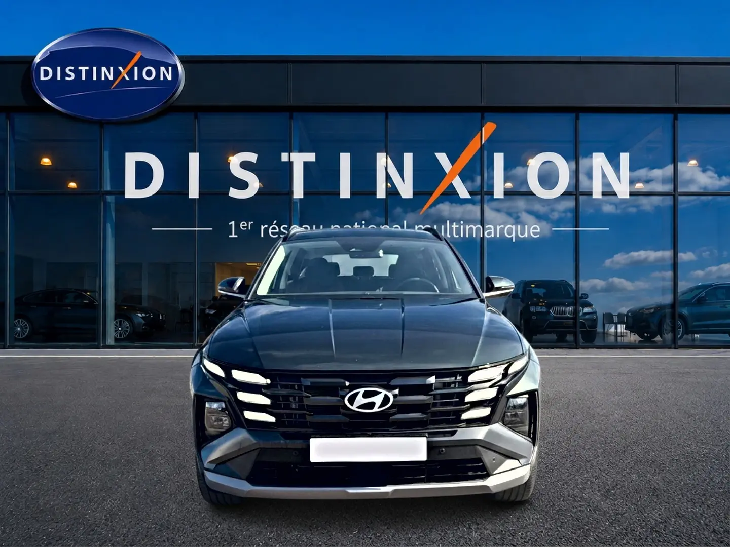 Vue avant d'un Hyundai Tucson vert 2026 garé devant une vitrine avec logo Distinxion en arrière-plan.