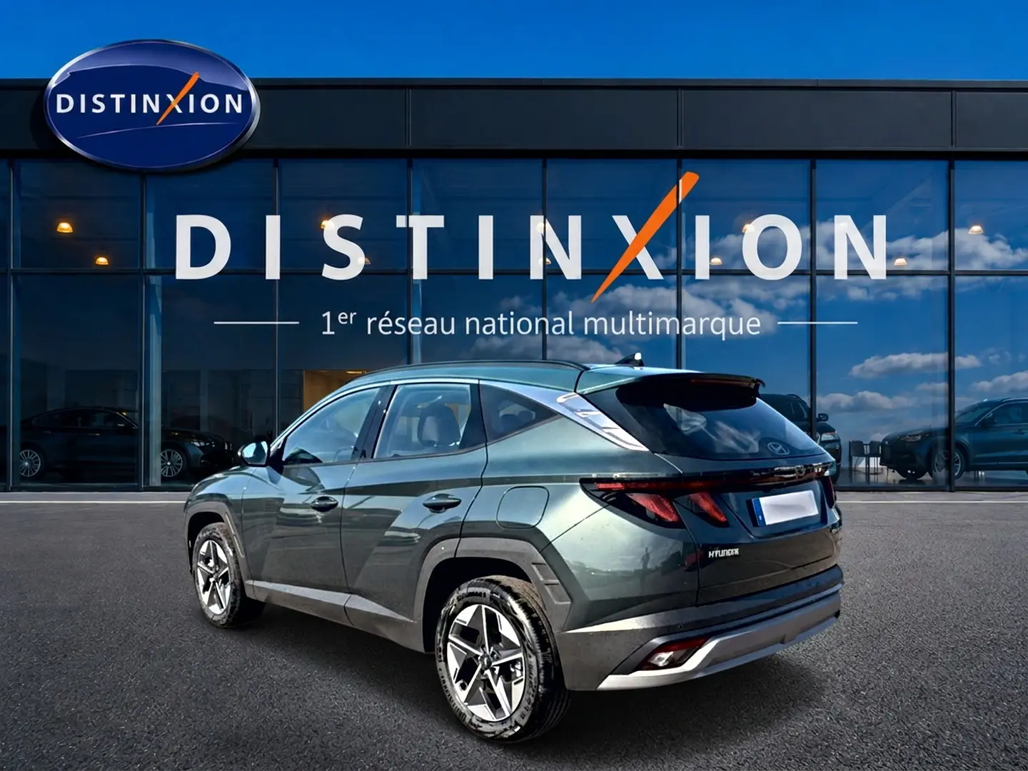 Vue 3/4 arrière gauche d'un Hyundai Tucson vert métallisé stationné devant une vitrine Distinxion.