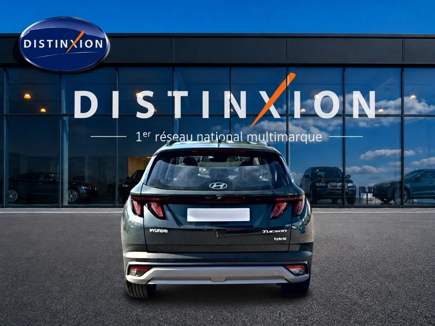 Vue arrière d'un Hyundai Tucson hybride vert 2026 garé devant une vitrine avec logo Distinxion.