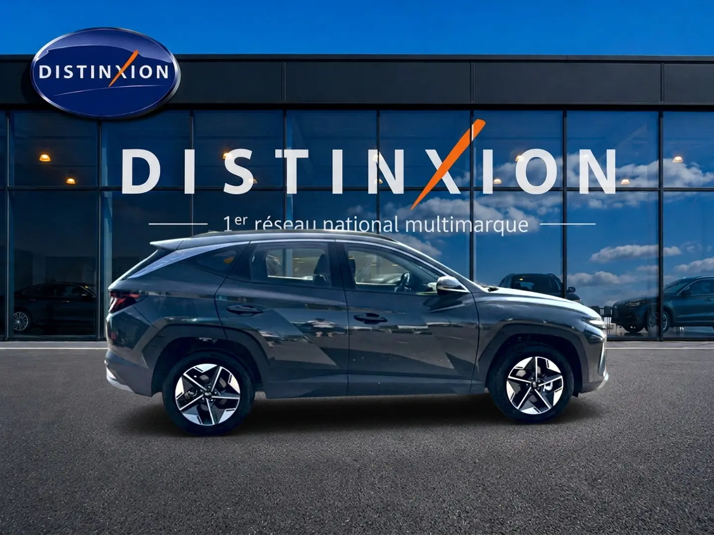 Profil côté gauche du Hyundai Tucson 2026 vert foncé avec jantes alliage, stationné devant une vitrine Distinxion.
