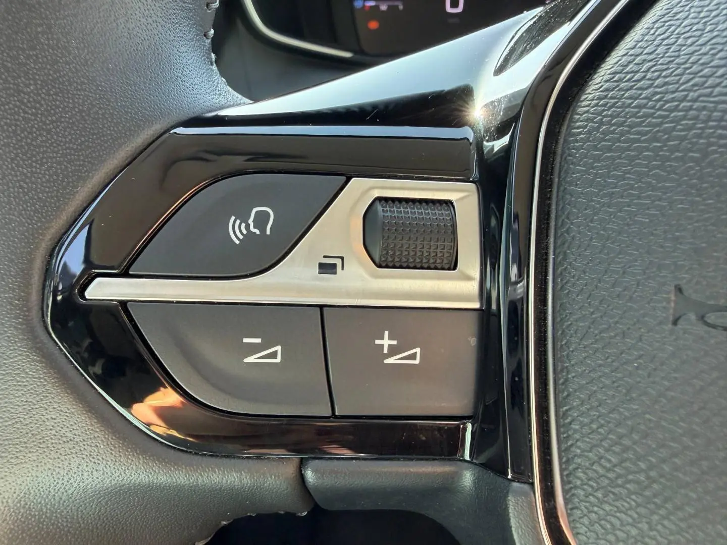 Gros plan sur les commandes audio et téléphone au volant d'une Peugeot 208 1.2 100ch gris Artense, côté gauche.