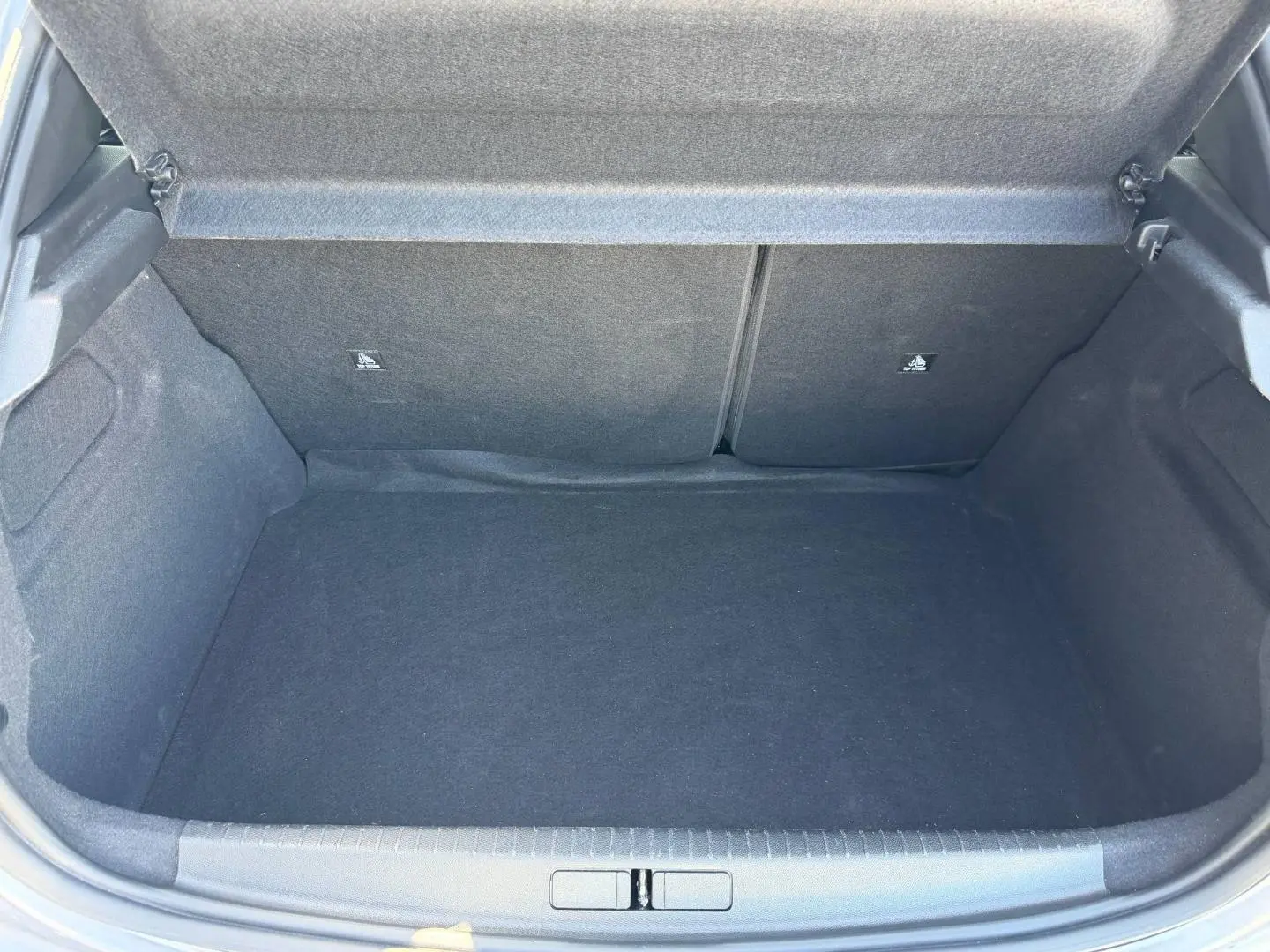 Coffre ouvert de la Peugeot 208 1.2 100ch gris Artense, montrant un espace de rangement propre et spacieux.