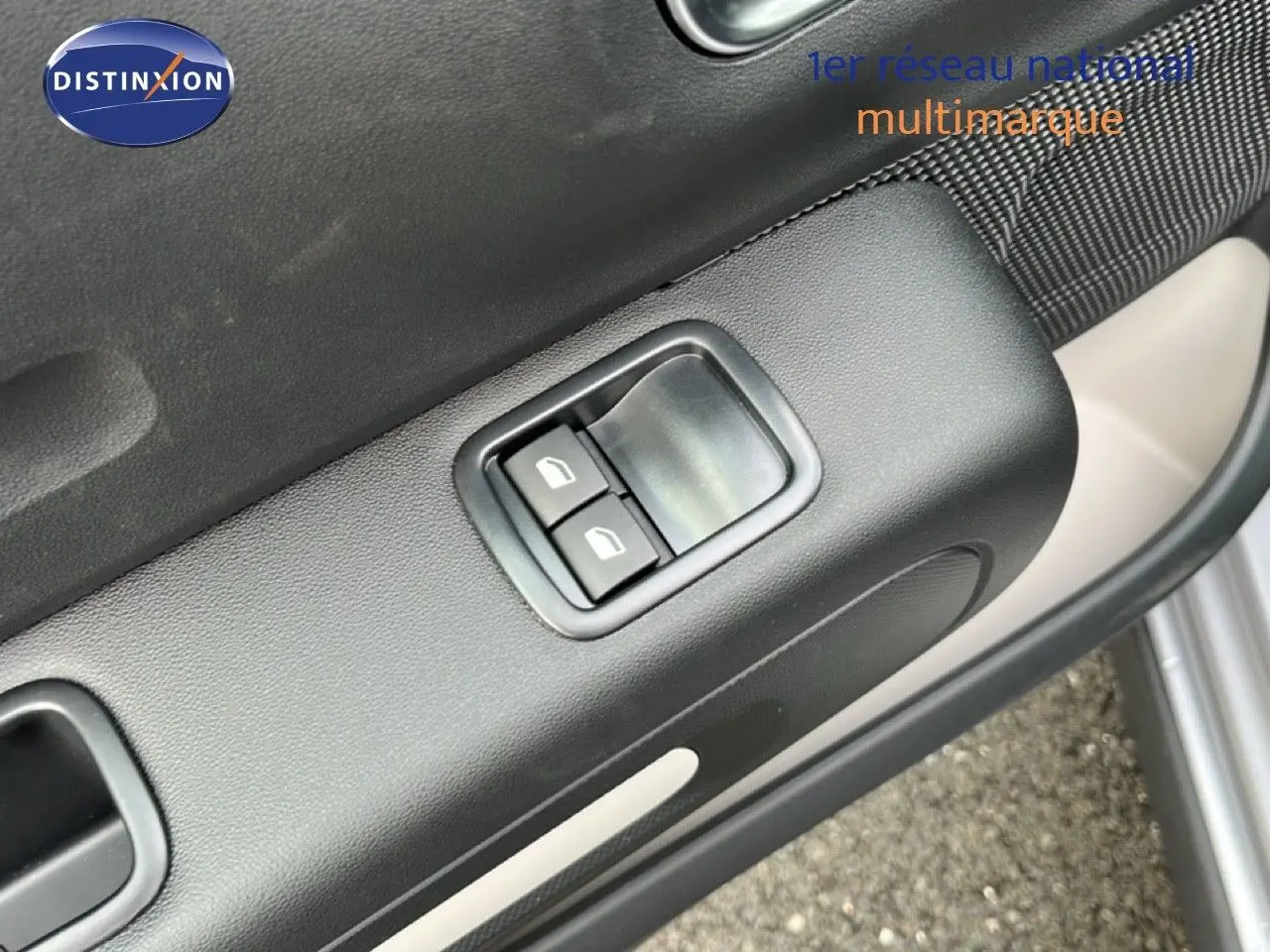 Détail des commandes des vitres électriques sur la porte avant gauche d'une Citroën C3 gris Artense 2024.