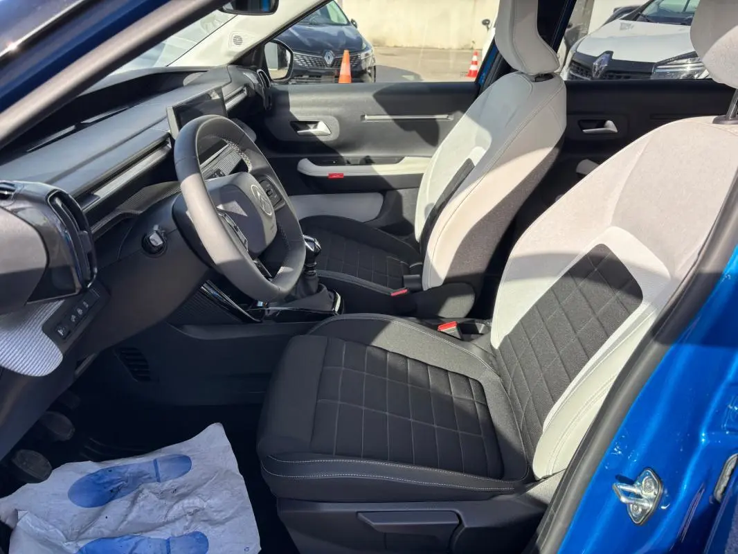 Vue intérieure côté conducteur de la Citroën C3 bleu 2025, sièges bi-ton noir et gris, volant et tableau de bord visibles.