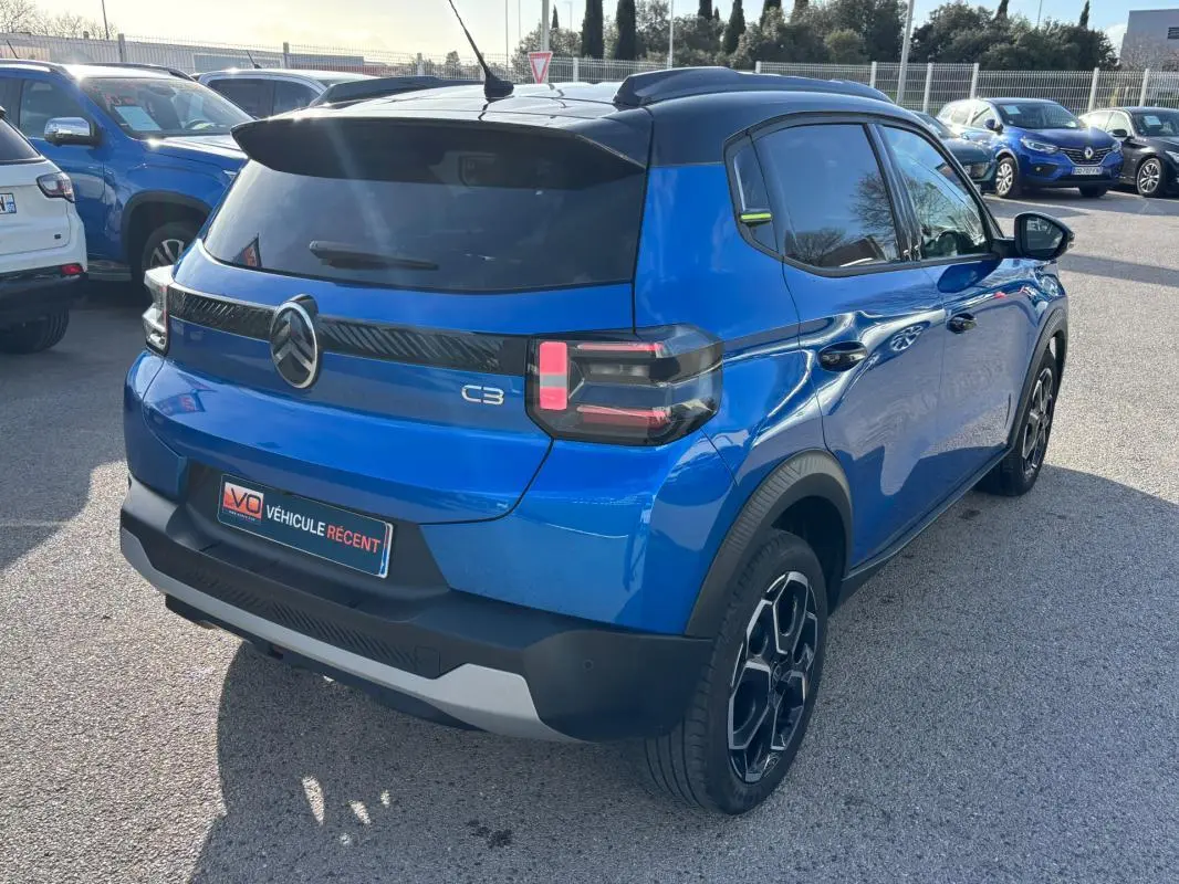 Vue 3/4 arrière droite d'une Citroën C3 bleu 2025 avec toit noir, jantes alliage 17 pouces et feux arrière LED.
