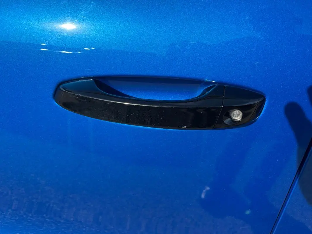 Poignée de porte noire sur la porte avant gauche d'une Citroën C3 bleu vif 2025, détail extérieur.