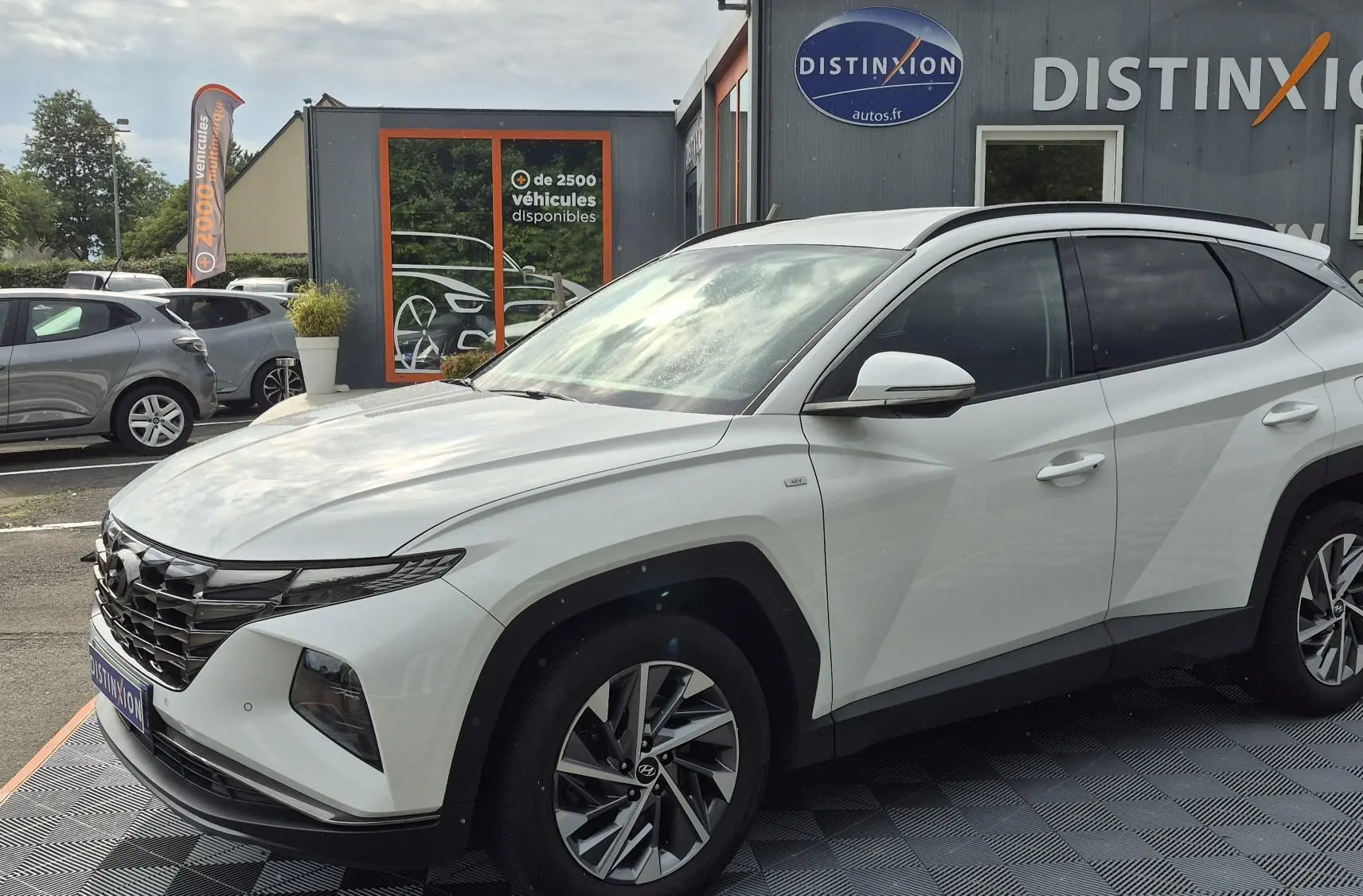 Hyundai Tucson blanc 2022 en 3/4 avant droit, avec calandre noire distinctive et jantes alliage bicolores.