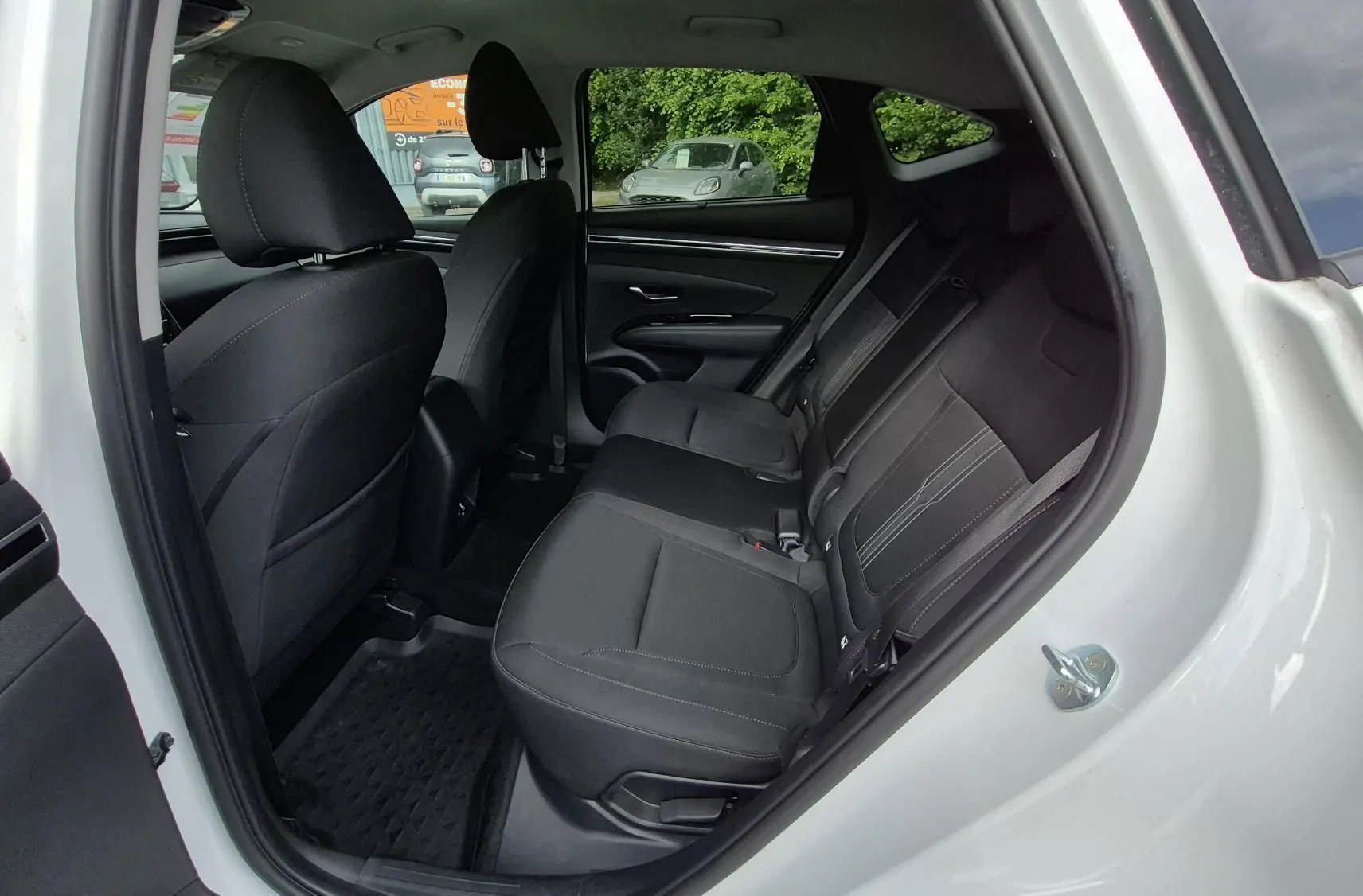Vue intérieure côté droit sur les sièges arrière noirs en tissu du Hyundai Tucson blanc 2022, porte ouverte.