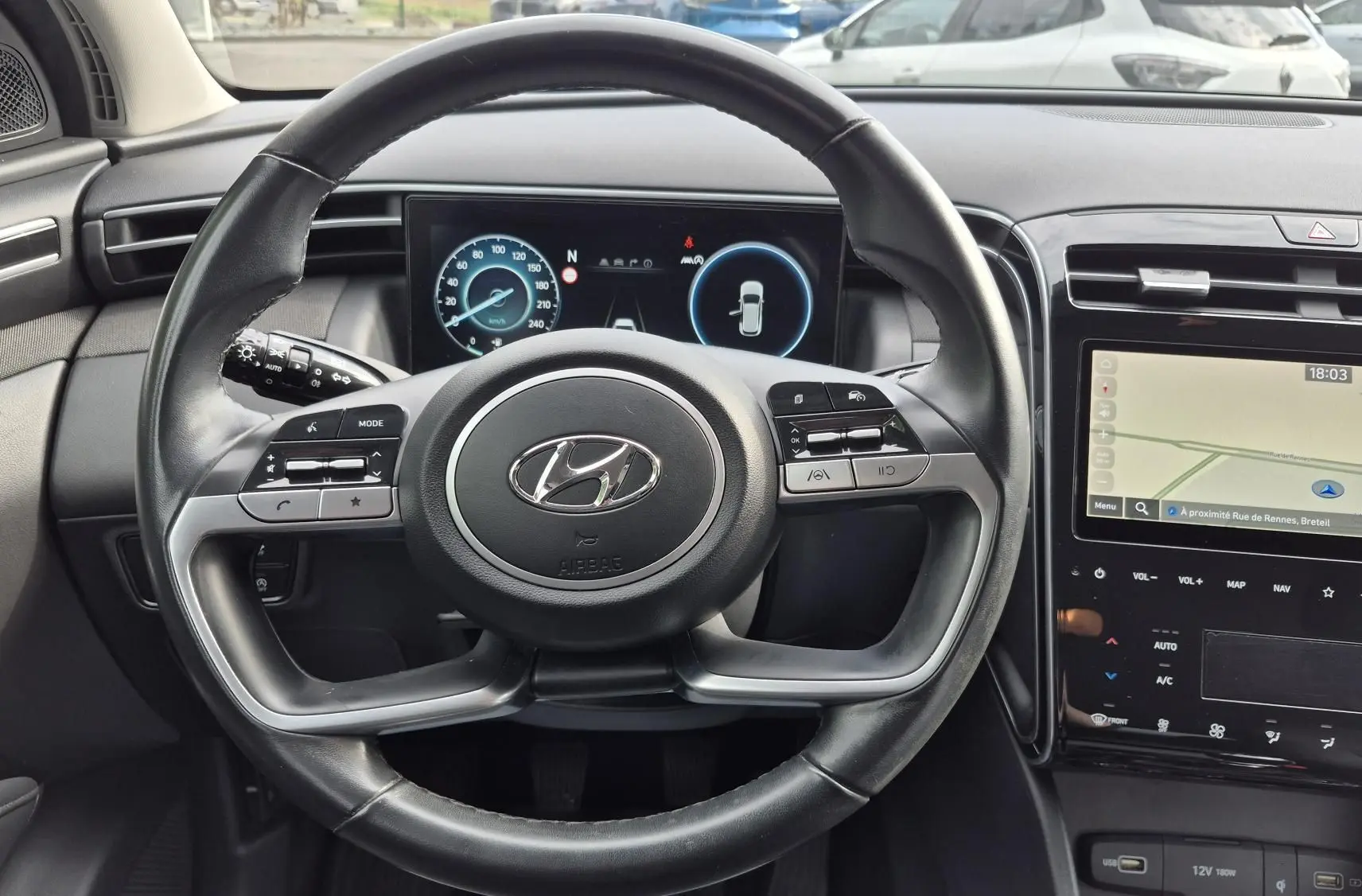 Vue intérieure frontale du volant noir de la Hyundai Tucson 2022 avec tableau de bord numérique et écran tactile GPS.