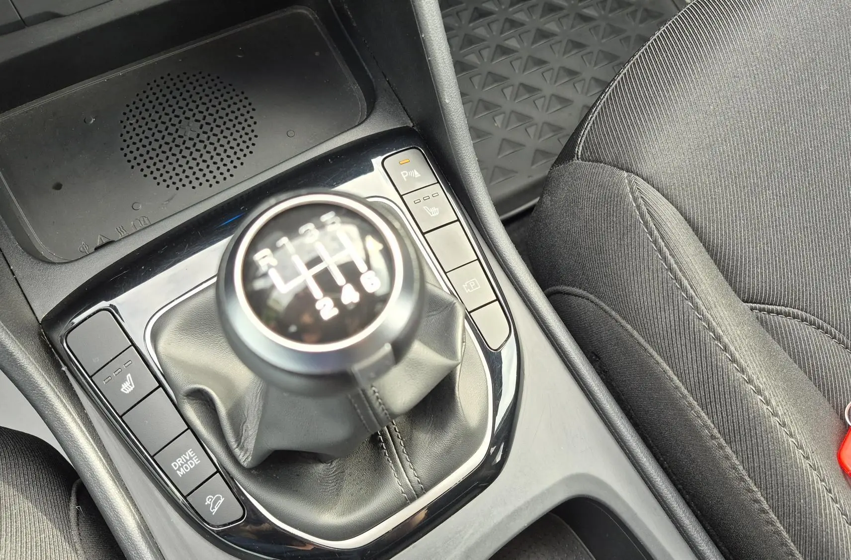 Gros plan sur le levier de vitesses manuel et la console centrale du Hyundai Tucson 1.6 CRDI blanc, avec siège tissu noir visible.