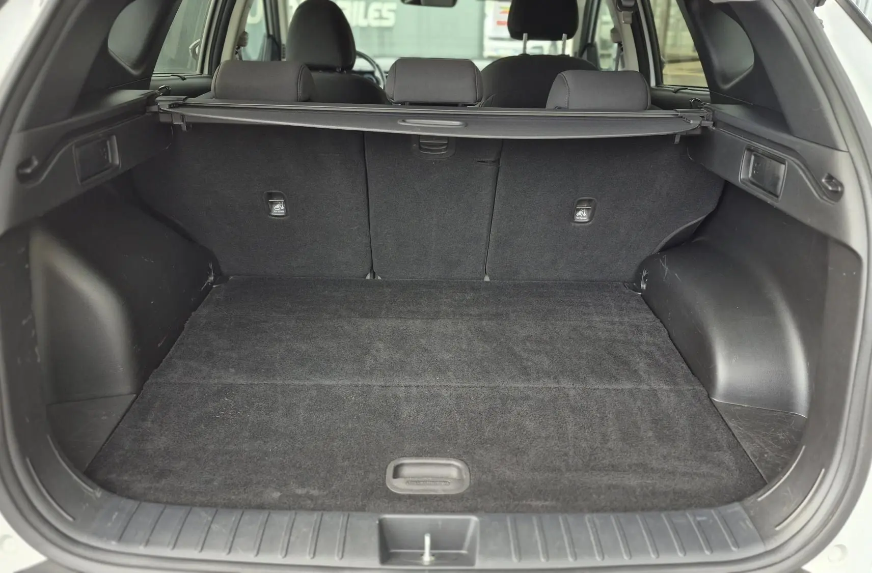 Vue arrière du coffre spacieux et propre d'un Hyundai Tucson blanc 2022, avec banquette arrière et cache-bagages visibles.