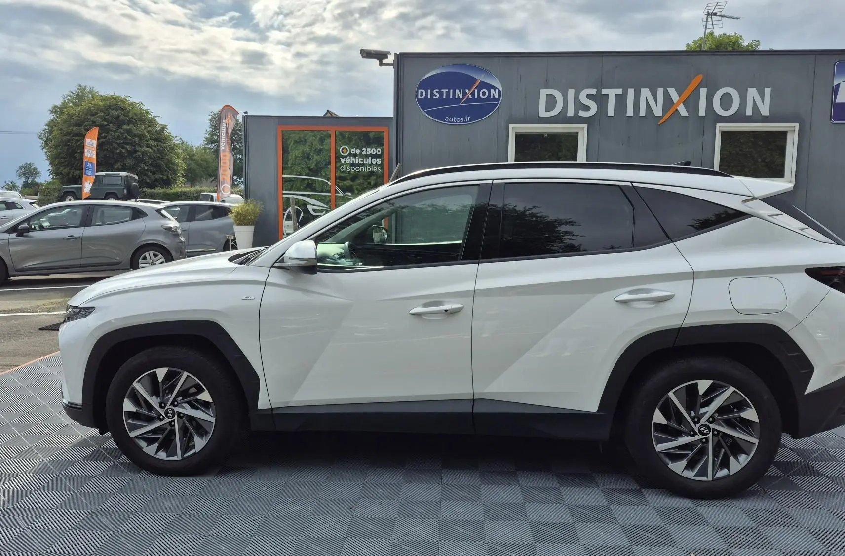 Vue de profil côté gauche d’un Hyundai Tucson blanc 2022 avec jantes alliage bicolores et vitres teintées.
