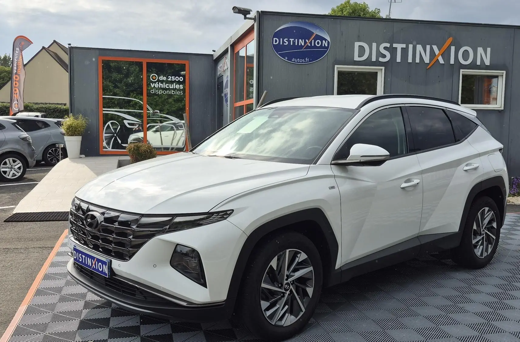 Vue 3/4 avant droit d’un Hyundai Tucson blanc 2022 avec calandre noire et jantes alliage bicolores.
