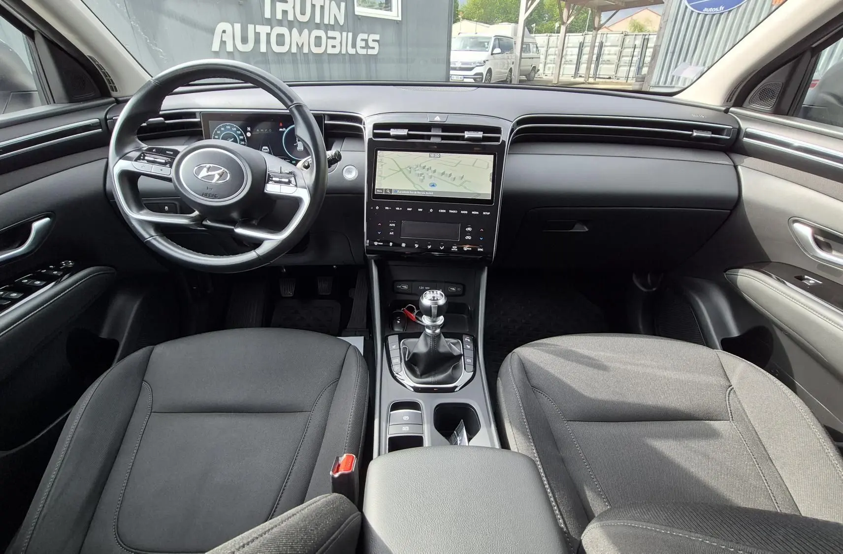 Vue intérieure frontale du Hyundai Tucson 2022, montrant le volant, la console centrale avec écran tactile et la boîte manuelle.