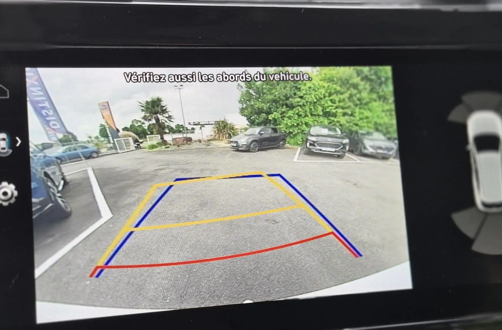 Vue caméra de recul du Hyundai Tucson blanc 2022, avec lignes de guidage colorées sur un parking extérieur.