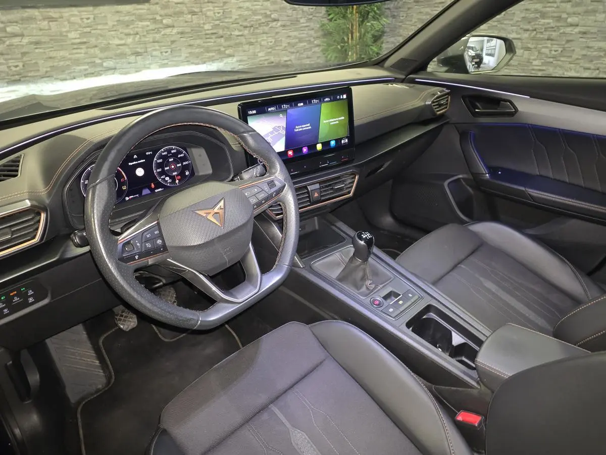 Vue intérieure côté conducteur du CUPRA Formentor 2023, tableau de bord noir avec volant sport, écran tactile et boîte manuelle.