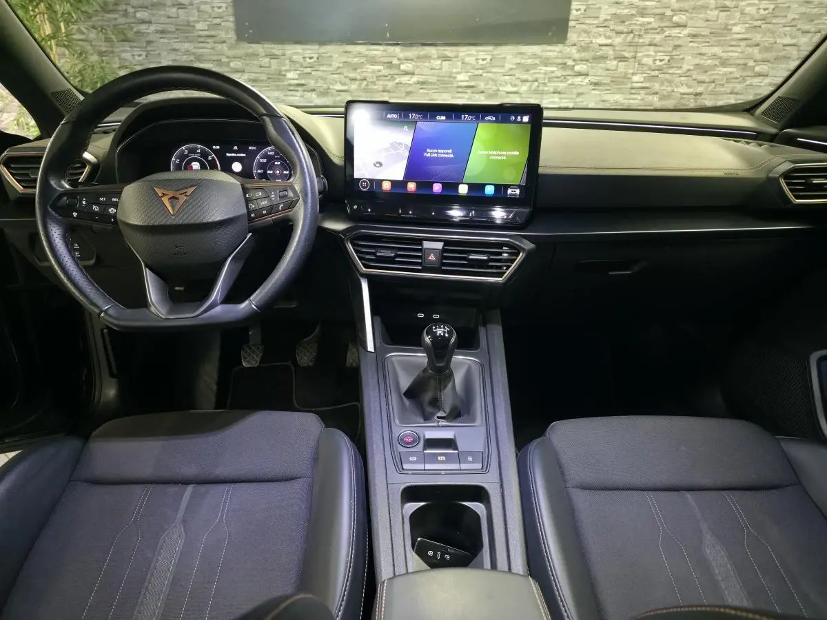 Vue intérieure frontale du tableau de bord et volant noir du CUPRA Formentor avec écran tactile et levier de vitesse manuel.