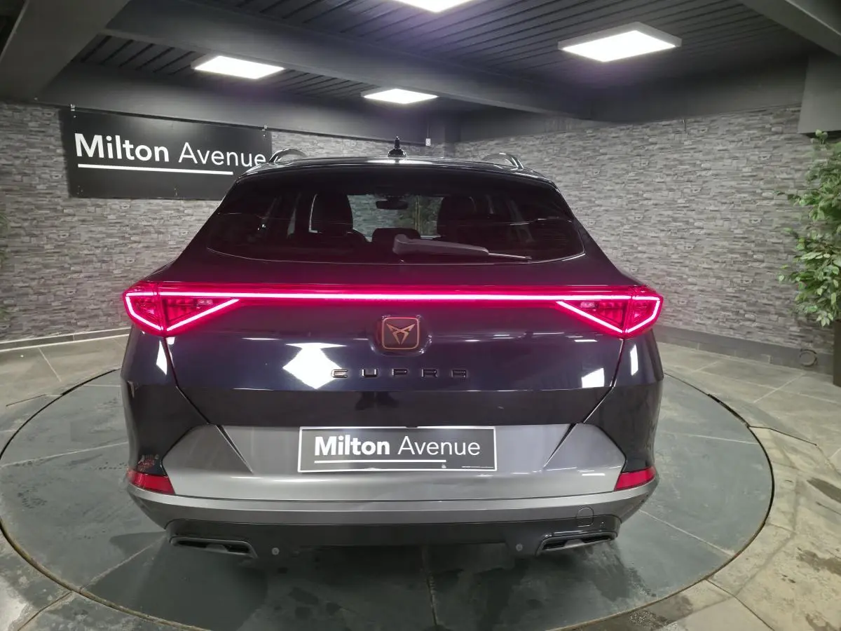 Vue arrière d'une CUPRA Formentor bleu pétrole 2023 avec hayon électrique et bandeau LED arrière lumineux.