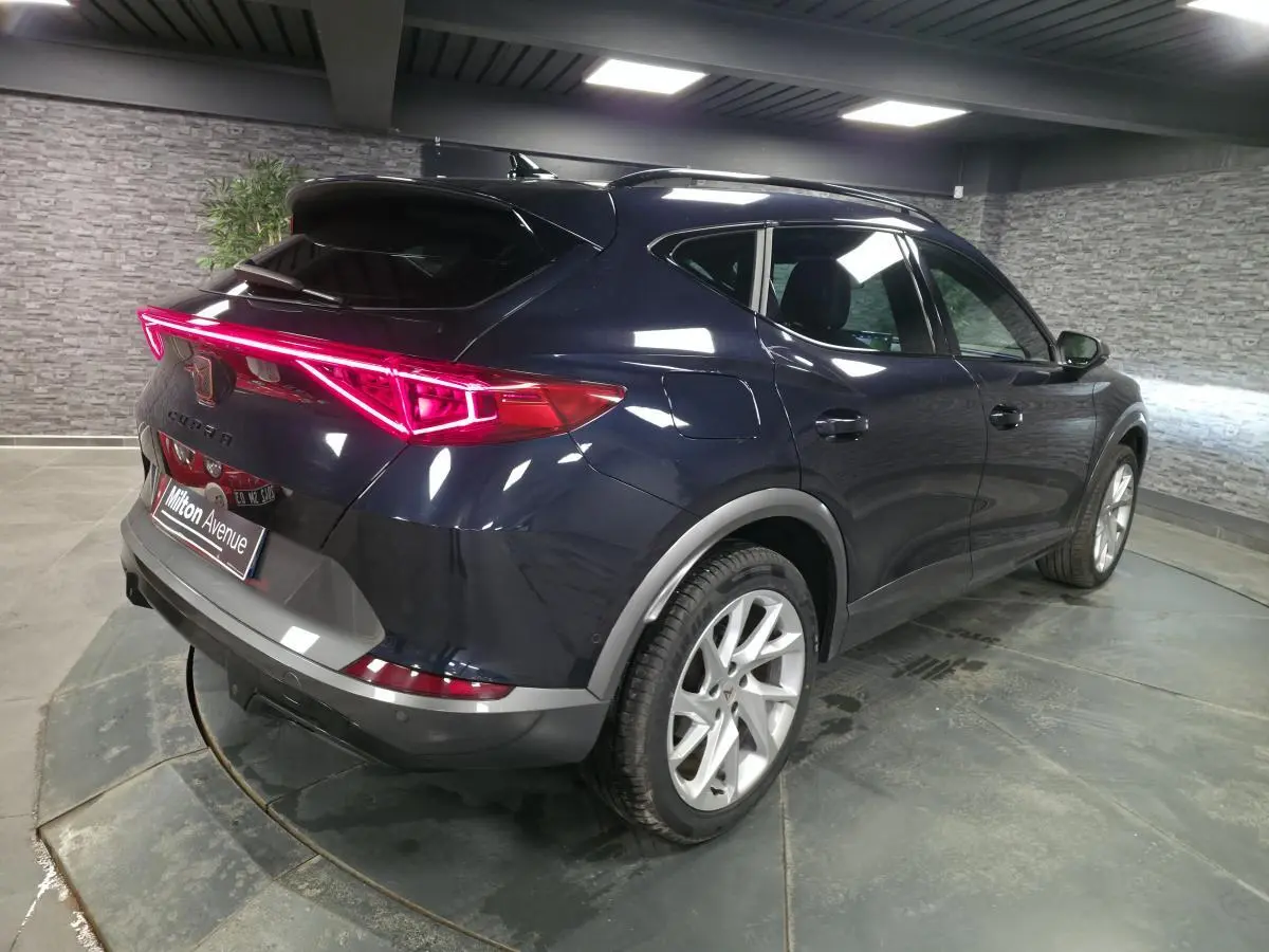 Vue 3/4 arrière droite du CUPRA Formentor bleu pétrole 2023 avec bandeau LED arrière 'Infinite Light' allumé.