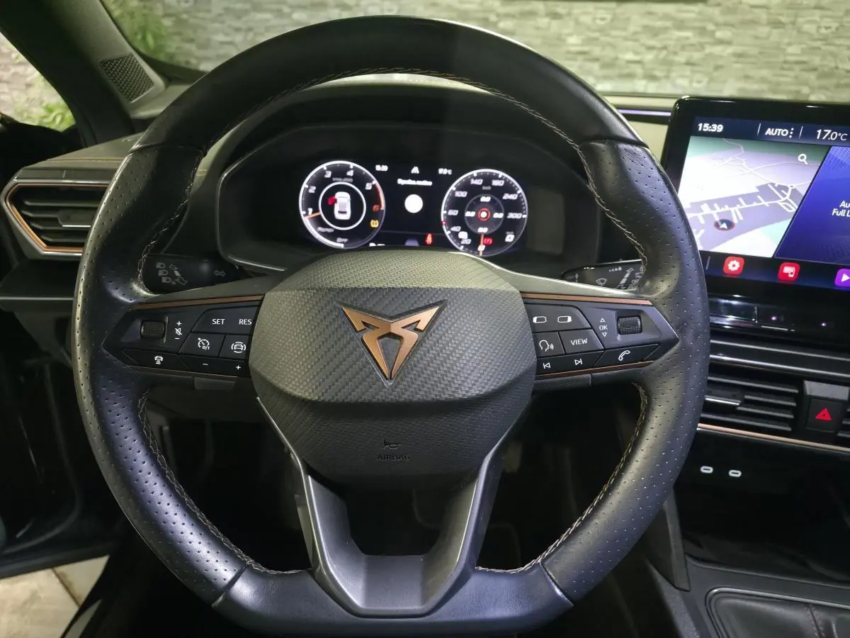 Vue rapprochée du volant sport en cuir noir avec logo CUPRA cuivre et tableau de bord digital du Formentor 2023.