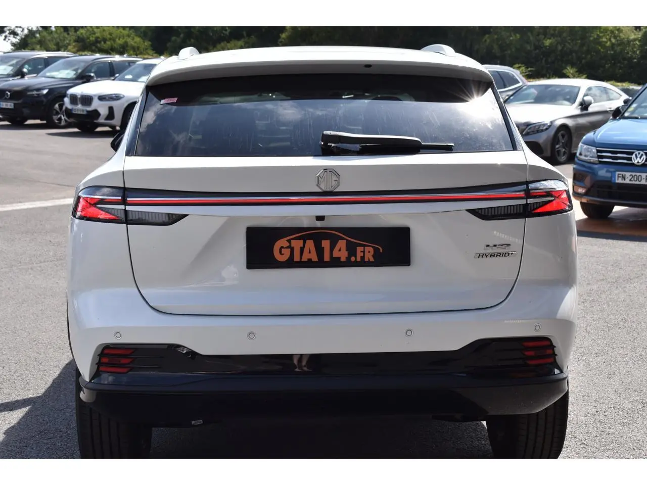Vue arrière d'un MG Motor EHS blanc 2026, avec feux reliés par une bande rouge et badge Hybrid+ visible à droite.