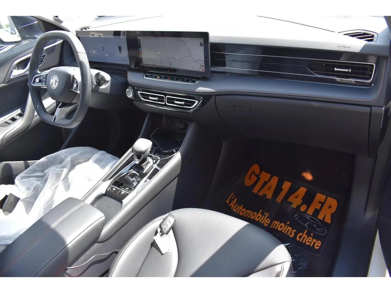 Vue intérieure côté conducteur du MG MOTOR EHS 1.5 Hybrid+ 224 ch Luxury 2026, tableau de bord moderne avec écran large et volant multifonction.