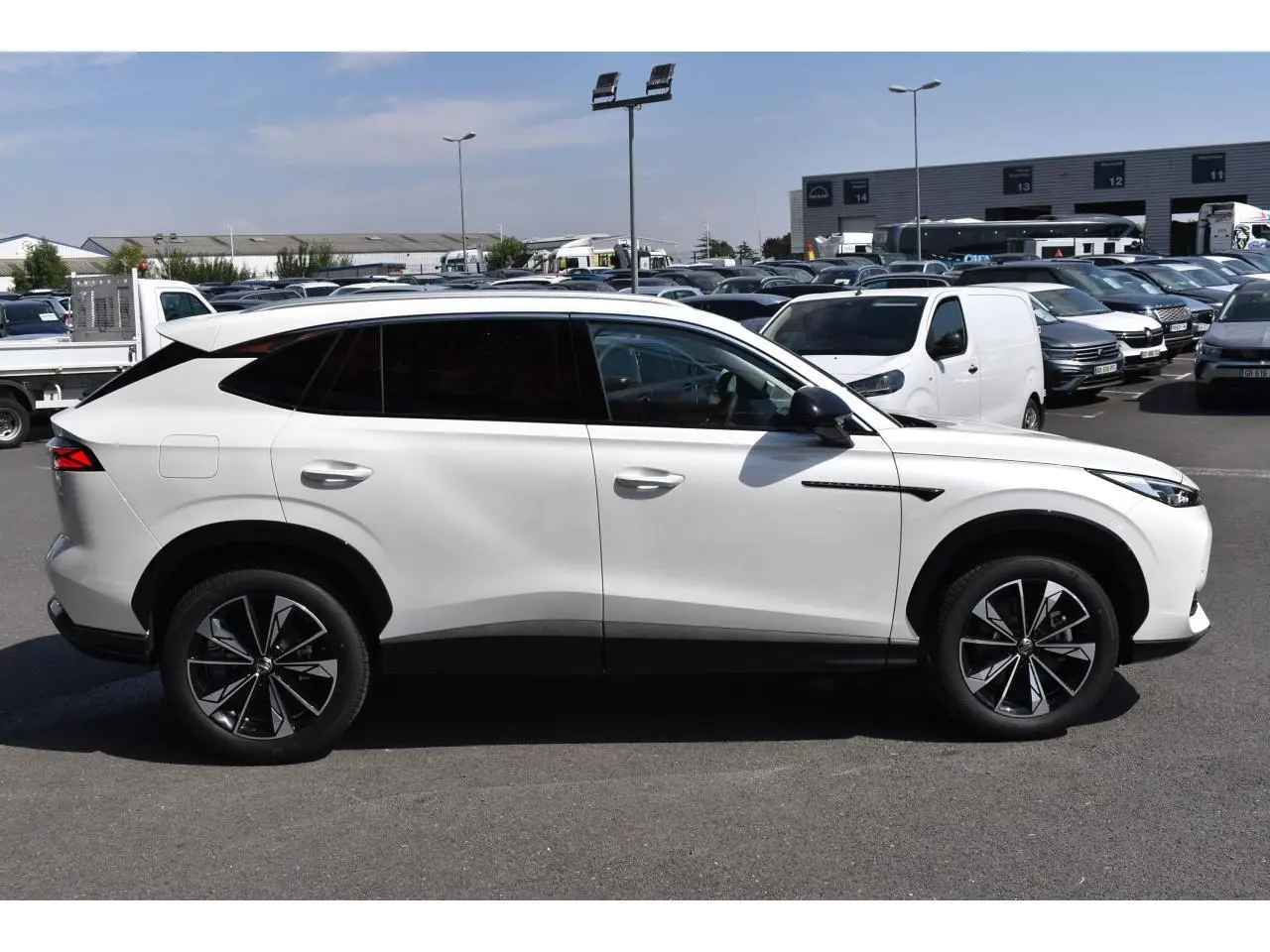 Vue de profil côté gauche du MG MOTOR EHS blanc 2026, SUV hybride avec jantes noires à motifs distinctifs.
