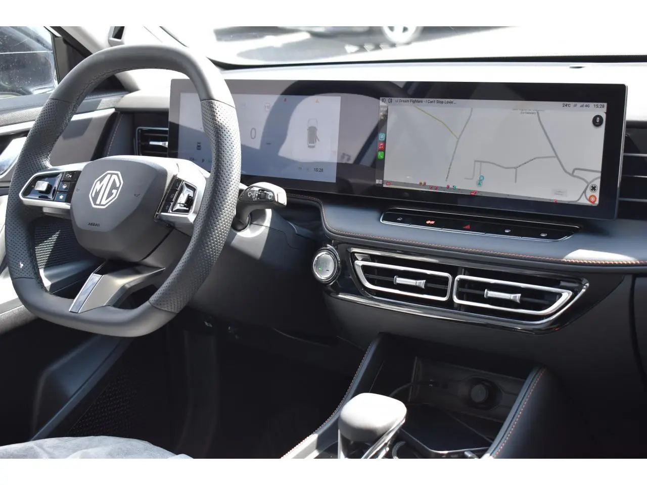 Intérieur du MG Motor EHS 1.5 Hybrid+ 224 ch Luxury 2026, vue du tableau de bord avec écran large et volant multifonction noir.