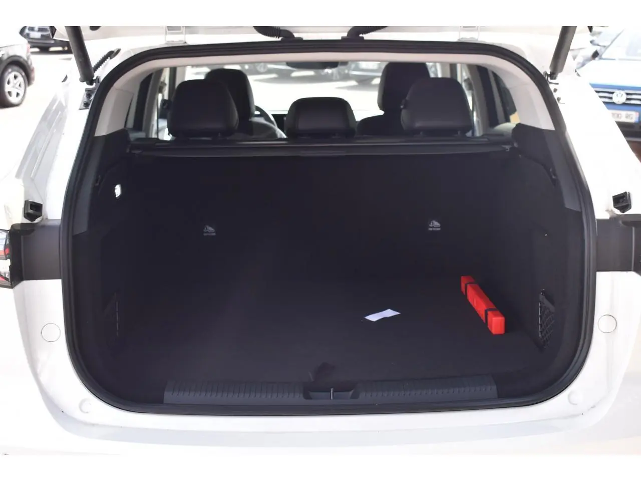 Coffre ouvert vu de l'arrière d'un MG MOTOR EHS blanc 2026, montrant un espace de chargement vide avec un triangle de sécurité rouge.