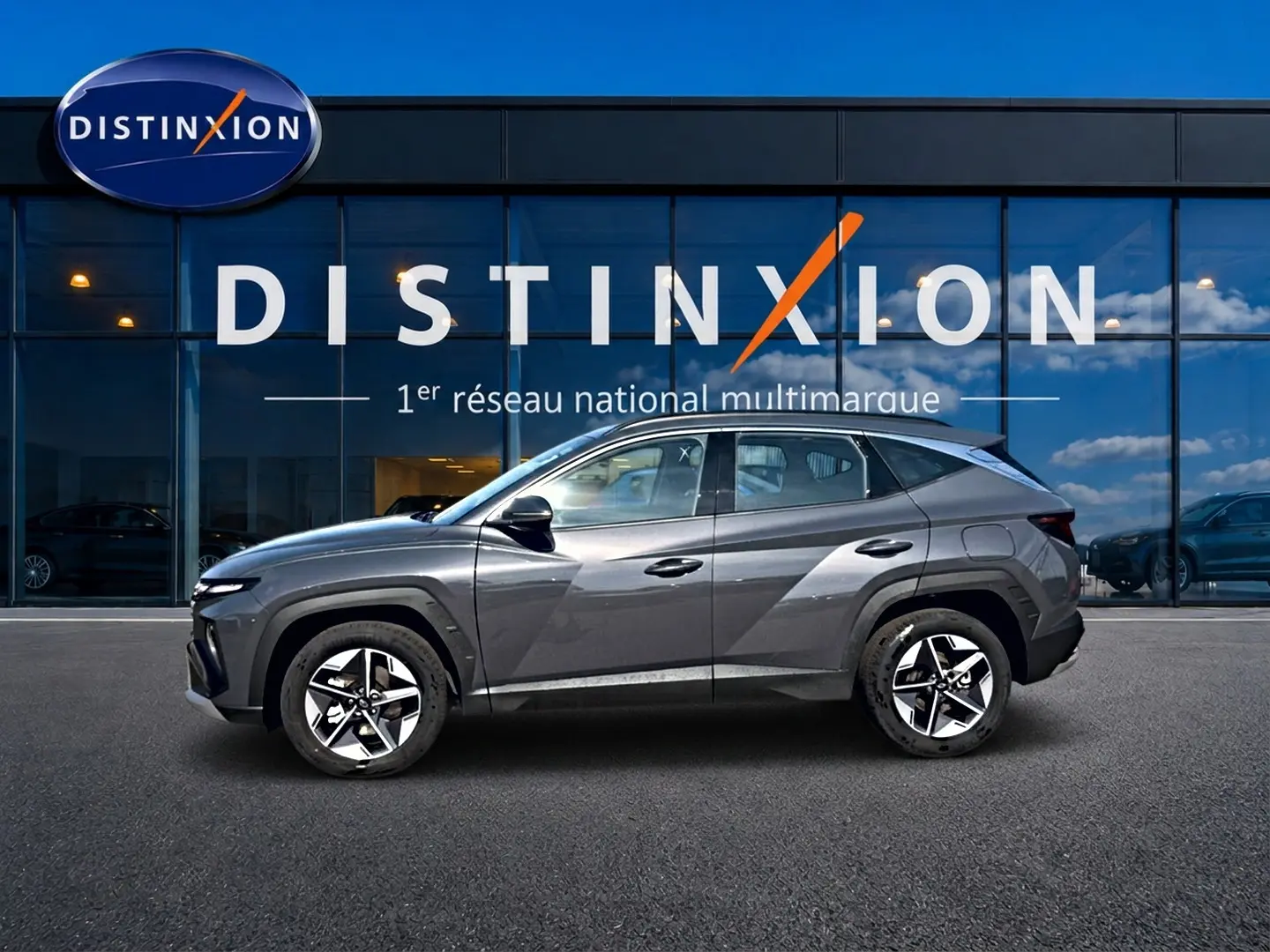 Vue de profil côté gauche d’un Hyundai Tucson gris ecotonic avec jantes alliage et lignes anguleuses marquées.