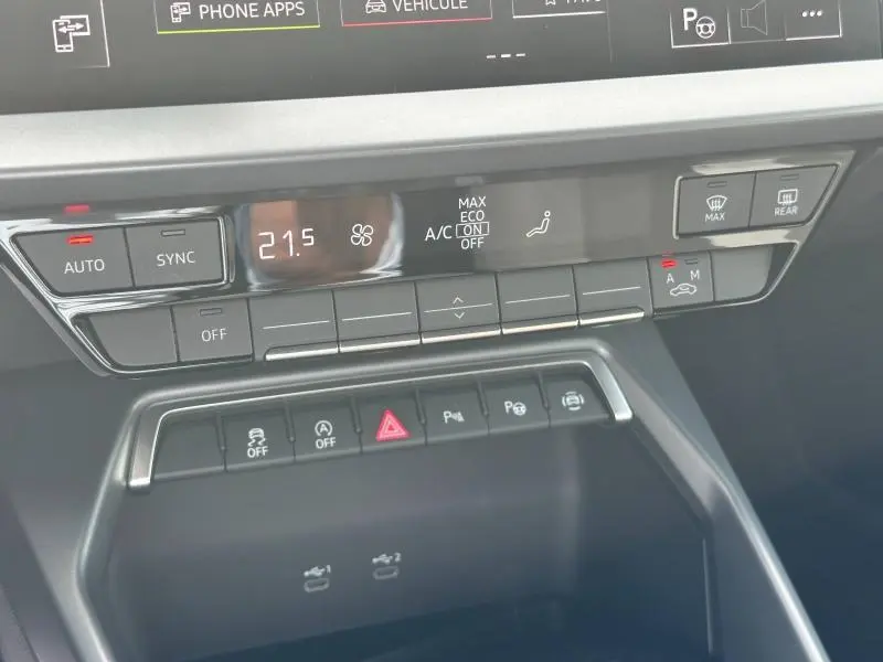 Détail du tableau de bord noir de l'Audi A3 Sportback 2024 montrant les commandes climatisation et aides à la conduite.