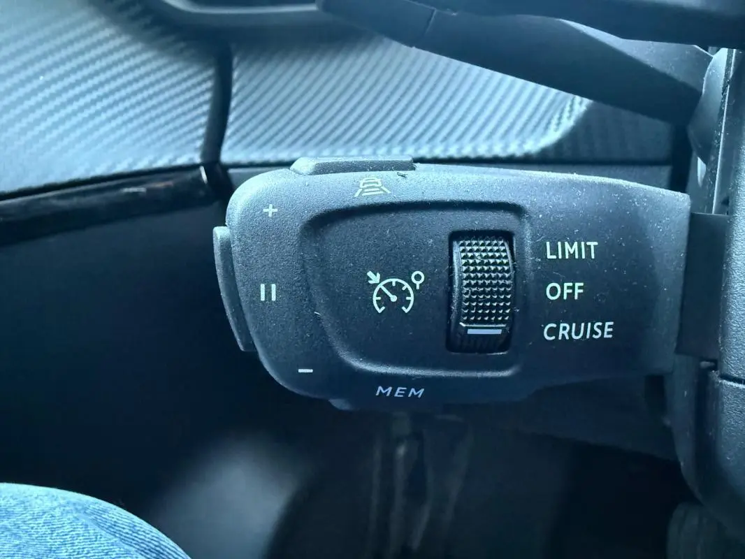 Gros plan sur la commande de régulateur de vitesse du Peugeot 208 Hybrid 110 e-DCS6 Allure, intérieur noir.
