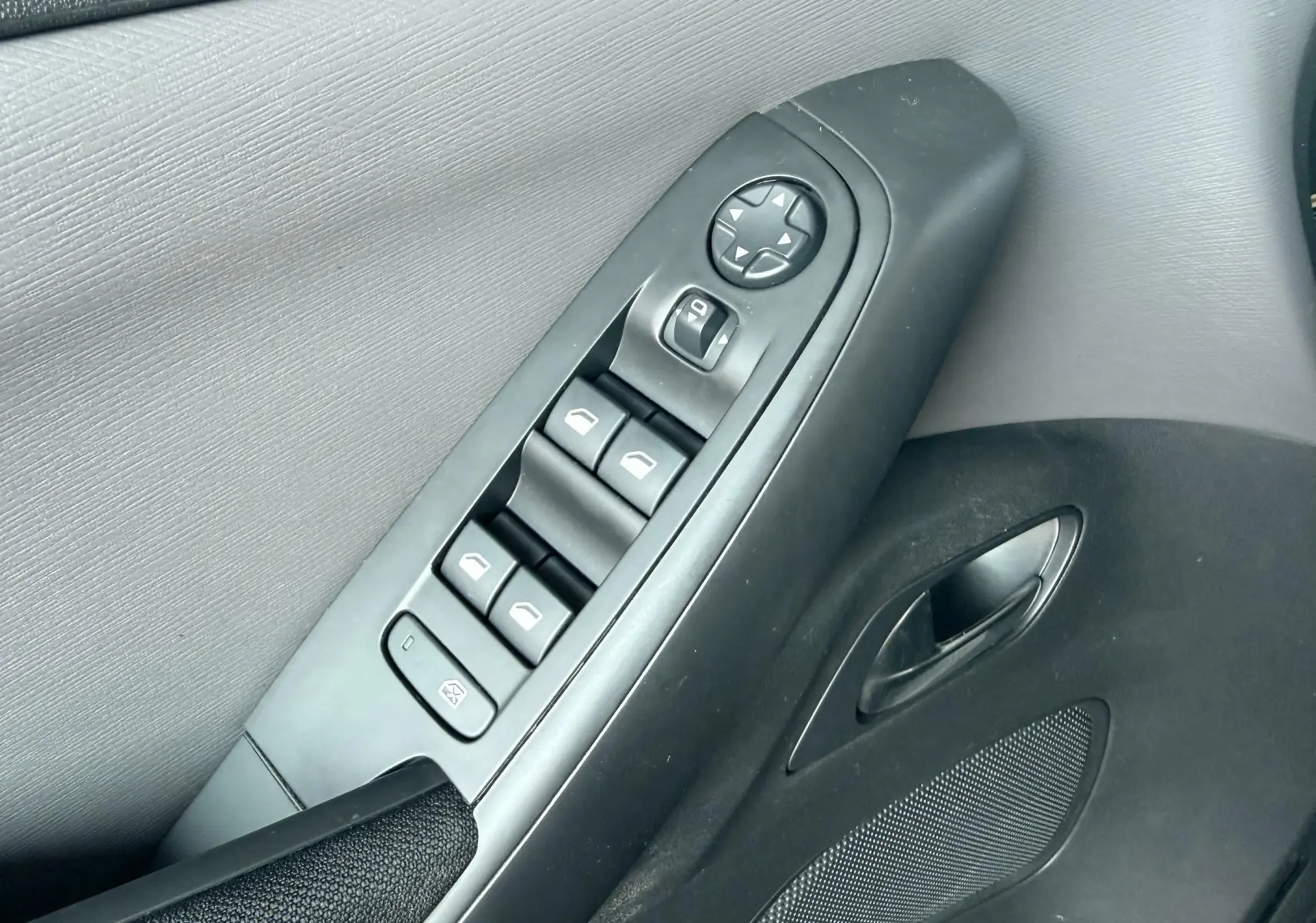 Vue rapprochée de la commande des vitres et rétroviseurs sur la porte côté conducteur d’une Citroën C4 Spacetourer noire.