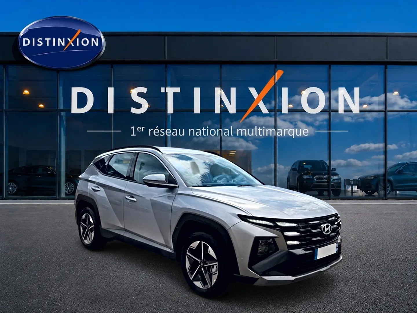 Hyundai Tucson gris shimmering en 3/4 avant droit, avec calandre distinctive et jantes alu 18 pouces.