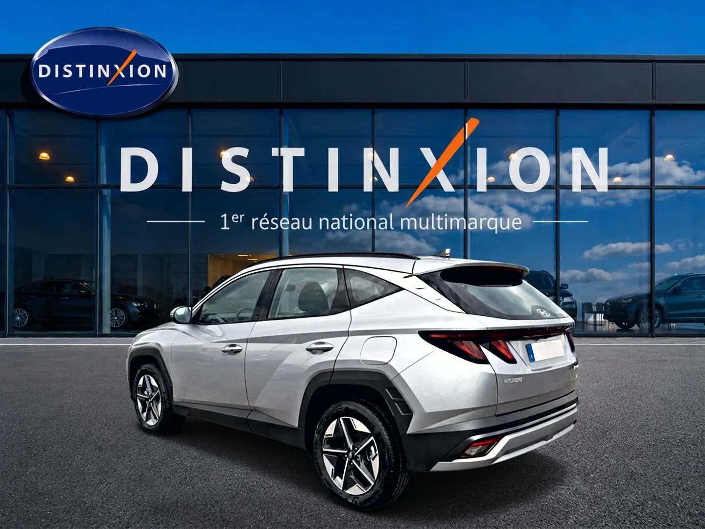 Vue 3/4 arrière droite du Hyundai Tucson gris shimmering 2026 devant un showroom Distinxion.