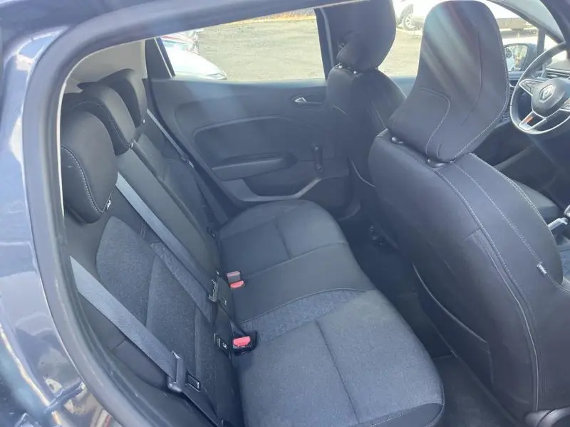 Vue intérieure arrière côté gauche de la Renault Clio gris titanium, sièges tissu noir avec surpiqûres blanches.