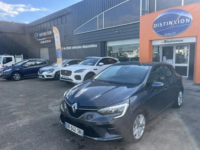 Renault Clio gris titanium vue 3/4 avant droit devant un concessionnaire Distinxion.