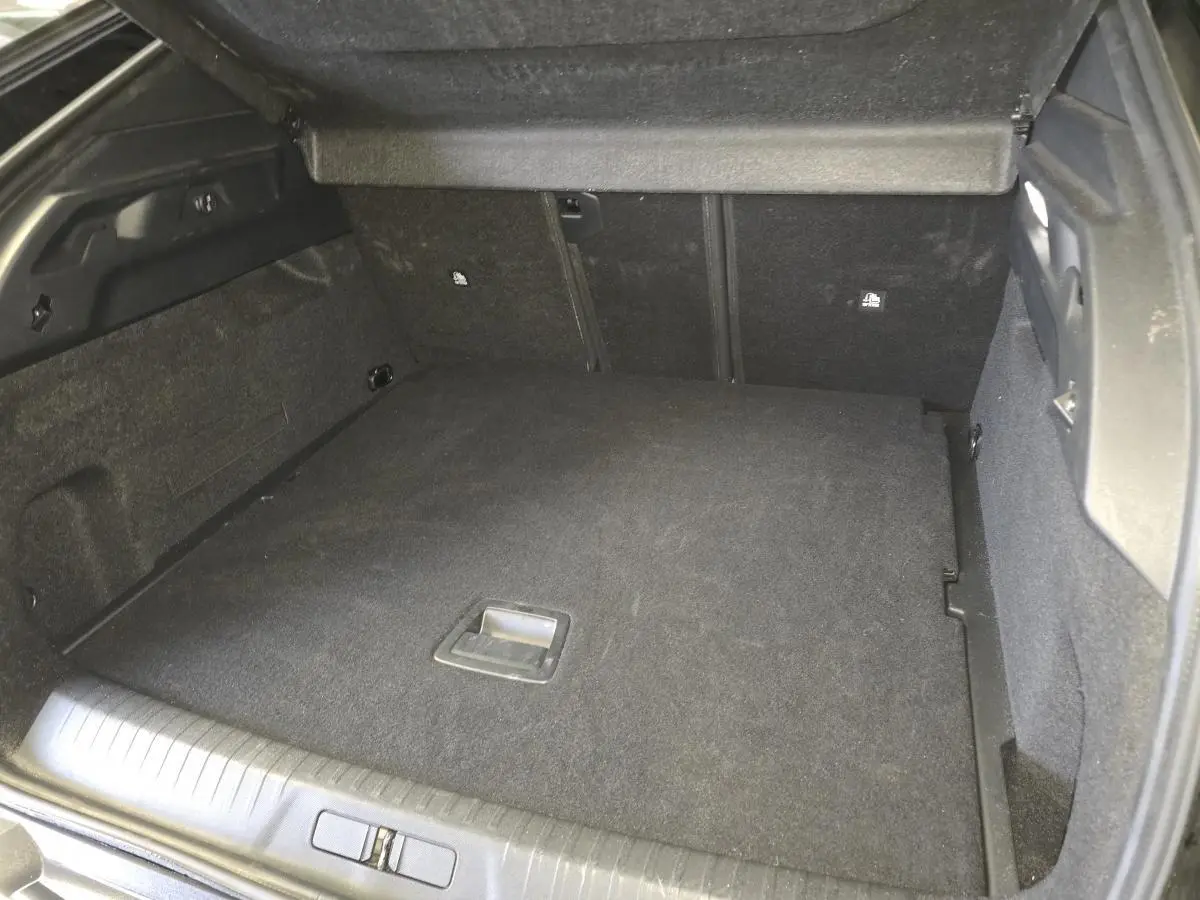 Coffre ouvert du Peugeot 3008 noir hybride 2025, vue intérieure montrant le plancher plat et les parois noires.