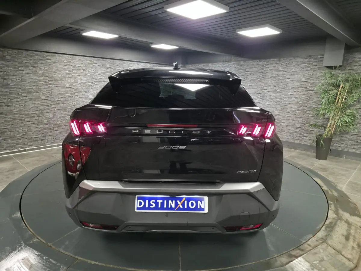 Vue arrière d’un Peugeot 3008 noir hybride 2025 avec feux arrière LED en forme de griffes et bandeau noir laqué.