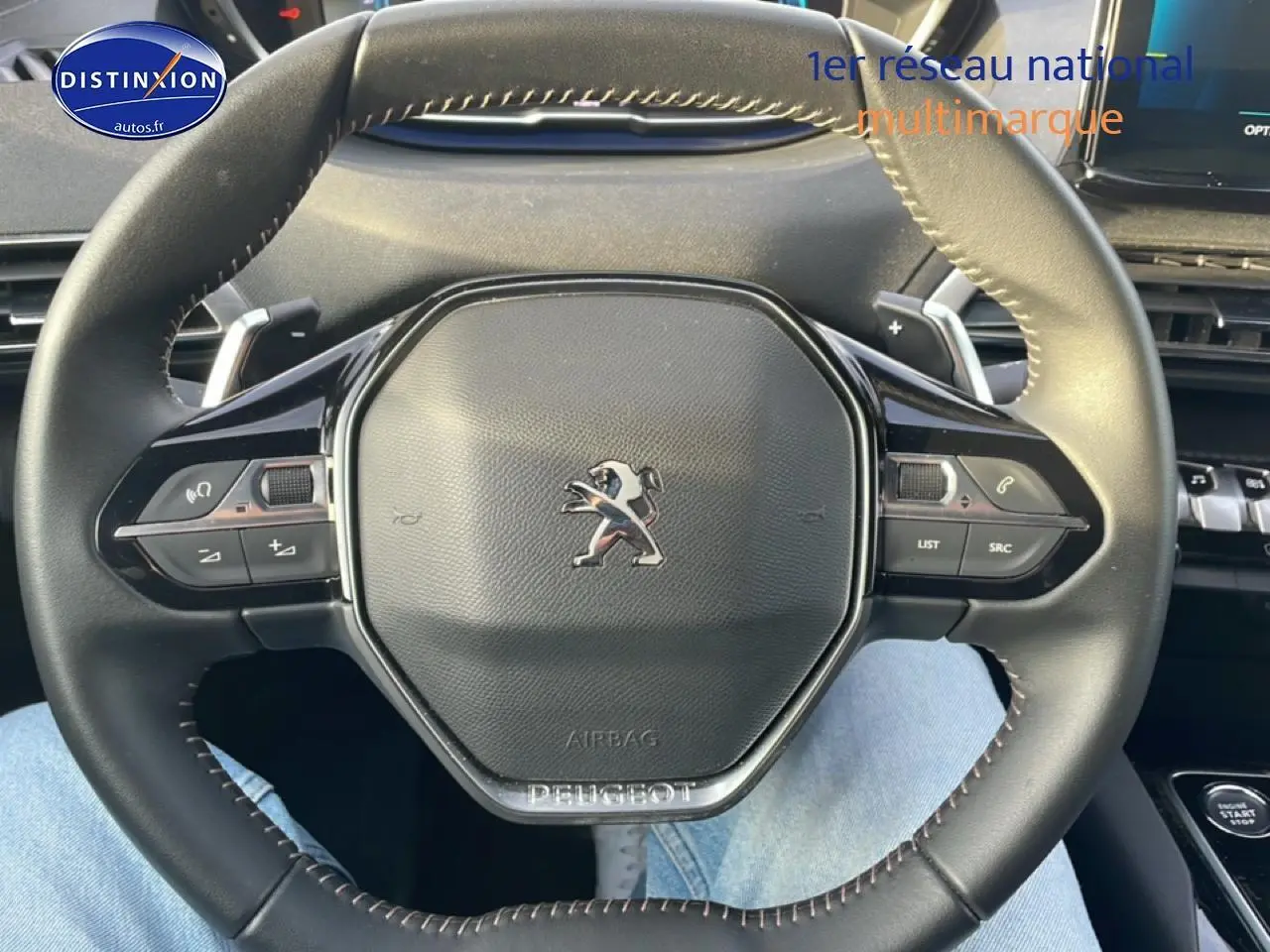 Volant cuir noir multifonction de Peugeot 3008 2024, vue rapprochée centrée sur le logo et commandes au volant.