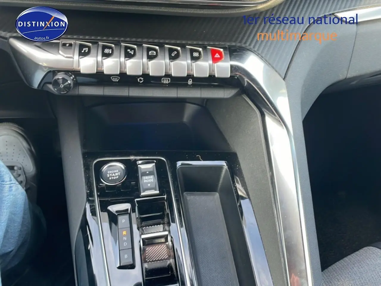 Vue intérieure centrée sur la console centrale noire brillante du Peugeot 3008 hybride 2024 avec commandes et levier de vitesses automatique.