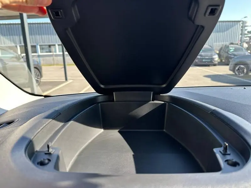 Vue rapprochée de la boîte de rangement ouverte sur le tableau de bord du Citroën Berlingo 2025 en intérieur noir.