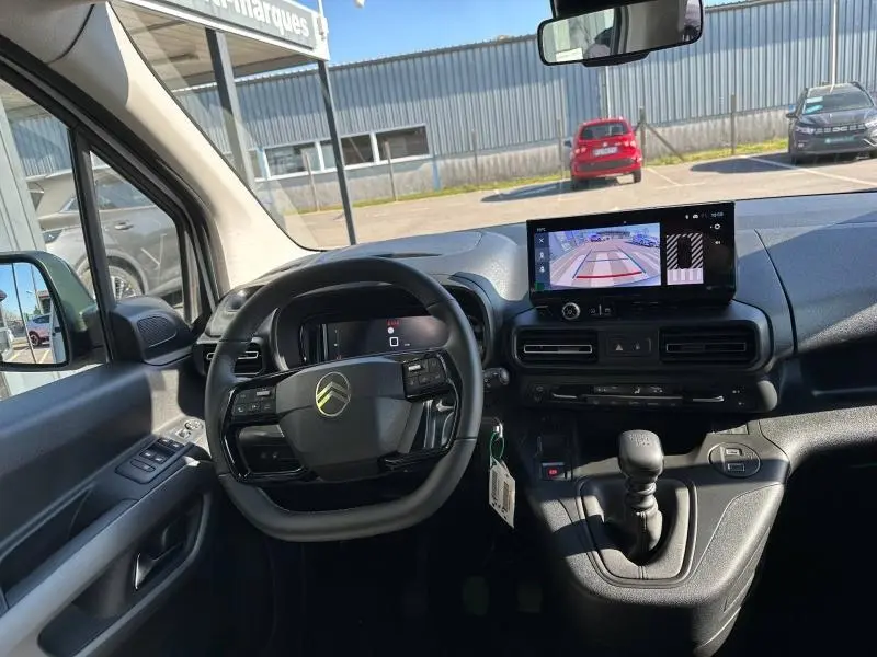 Vue intérieure avant du Citroën Berlingo 2025 avec tableau de bord noir et écran tactile affichant la caméra de recul.