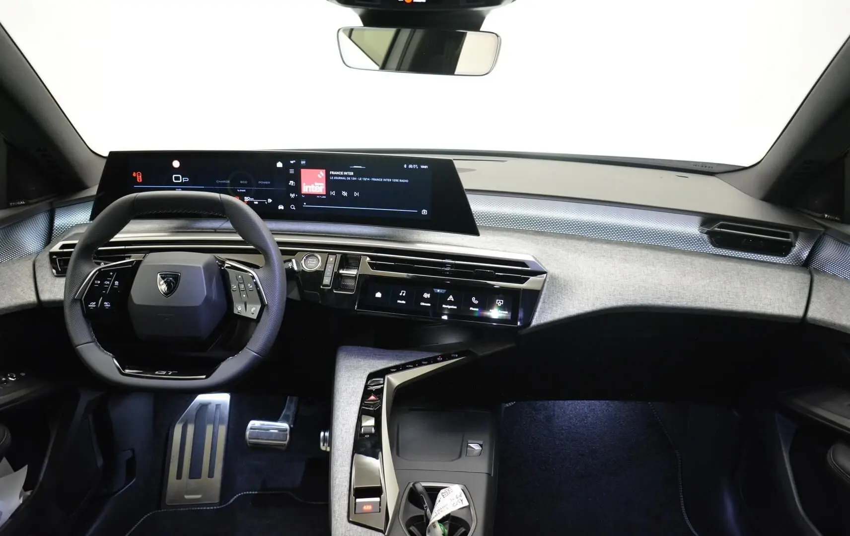 Vue intérieure avant du tableau de bord du Peugeot 3008 III Hybrid 145ch GT avec écran numérique panoramique et volant compact noir.