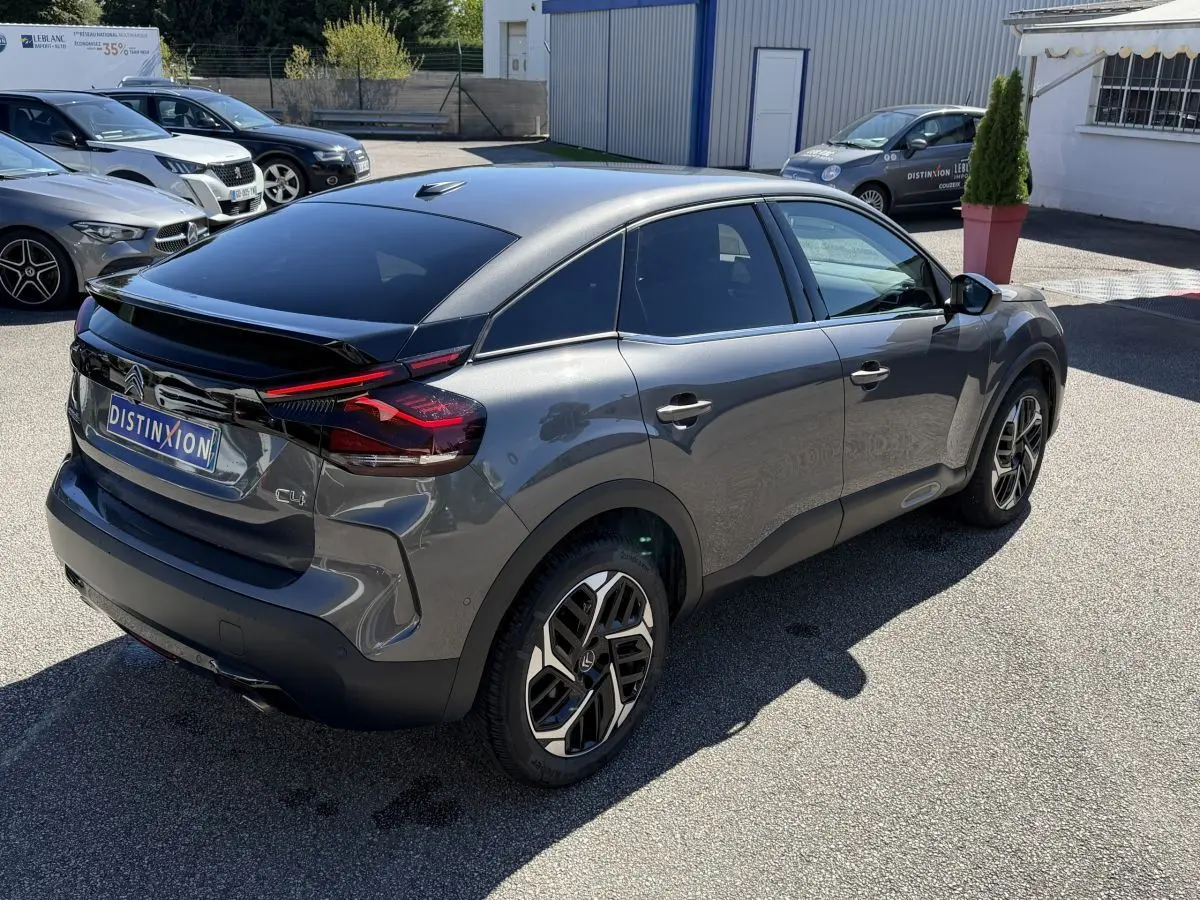 Vue 3/4 arrière droite d'une Citroën C4 PureTech 130 S&S Shine gris foncé avec feux arrière LED et jantes distinctives.