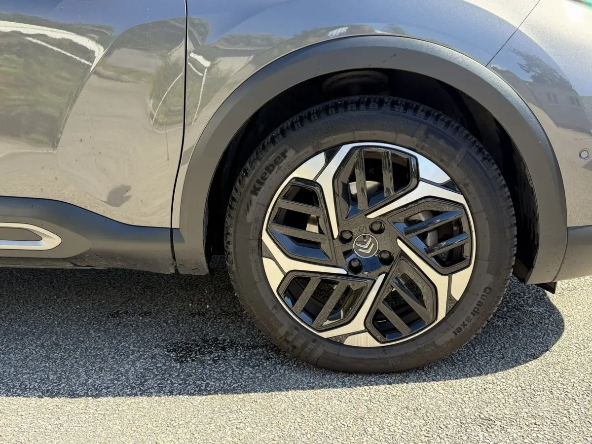 Gros plan sur la roue avant droite d'une Citroën C4 gris foncé, mettant en valeur la jante au design moderne bicolore.