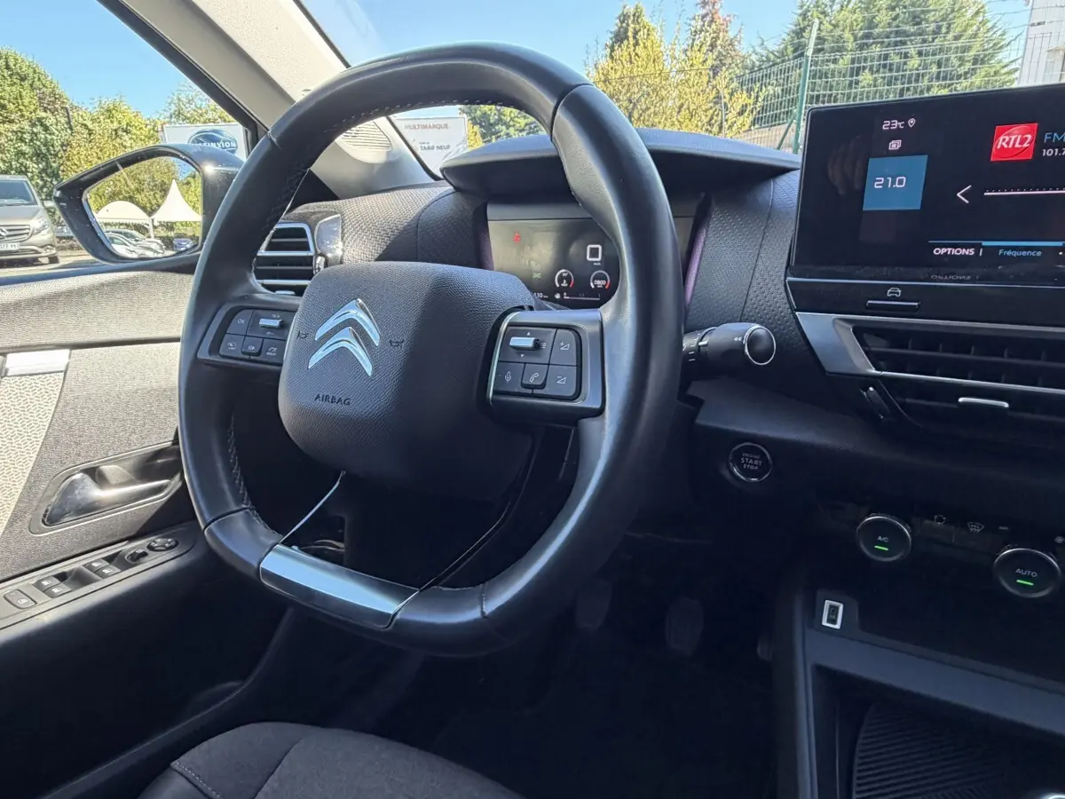 Vue intérieure centrée sur le volant cuir et tableau de bord digital de la Citroën C4 PureTech 130 S&S Shine 2022.