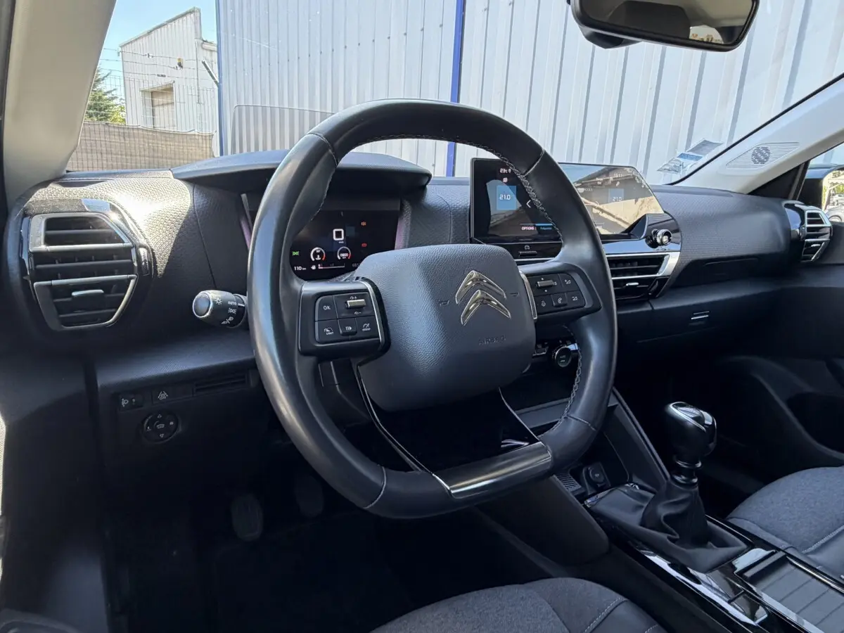 Vue intérieure centrée sur le volant cuir multifonctions et le tableau de bord numérique de la Citroën C4 2022.
