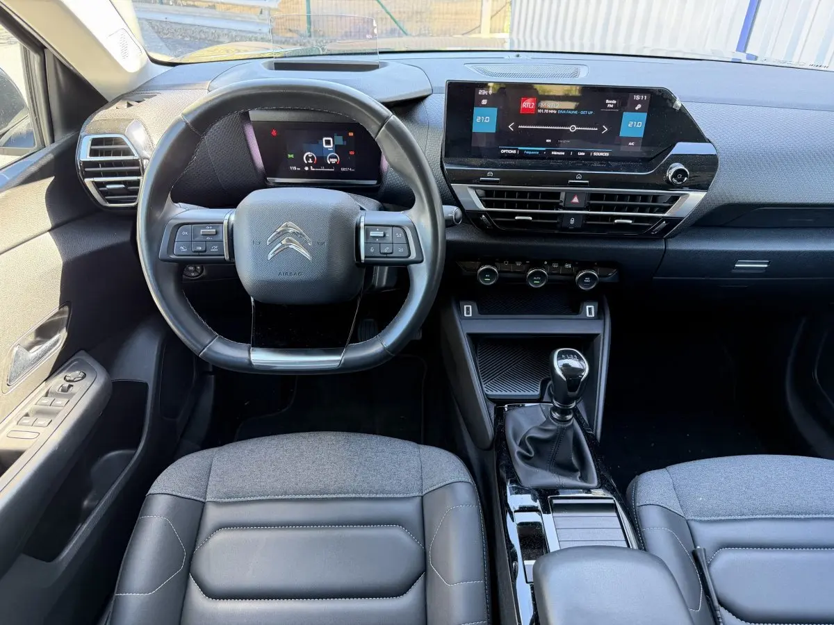 Vue intérieure avant centrée sur le volant cuir et tableau de bord numérique de la Citroën C4 PureTech 130 S&S Shine 2022.